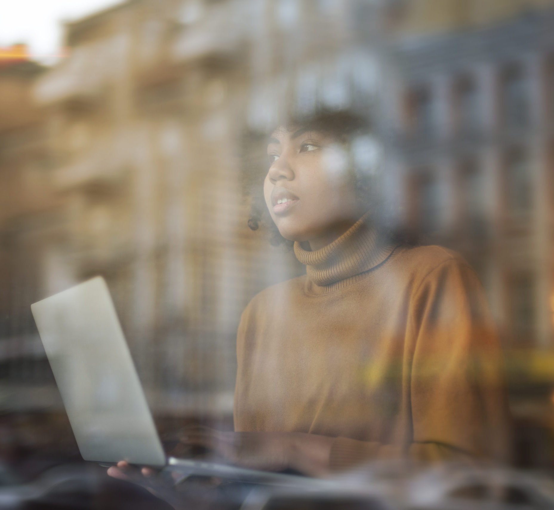 young woman at computer gazing out window