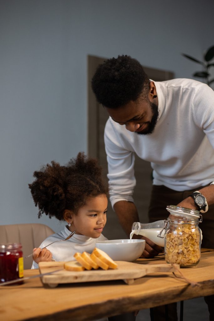 image of father pouring milk for daughter